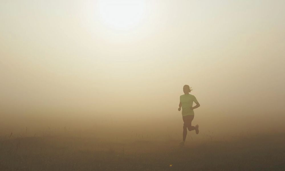 Solitary runner breaking through light fog, representing mental clarity emerging.