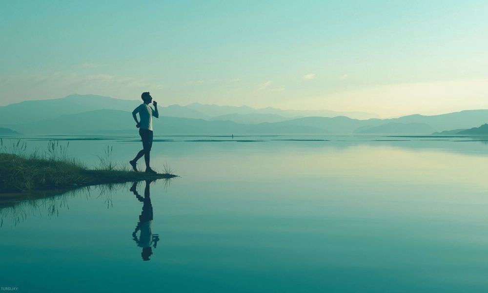 Runner standing alone by calm water, breathing deeply — representing emotional release.